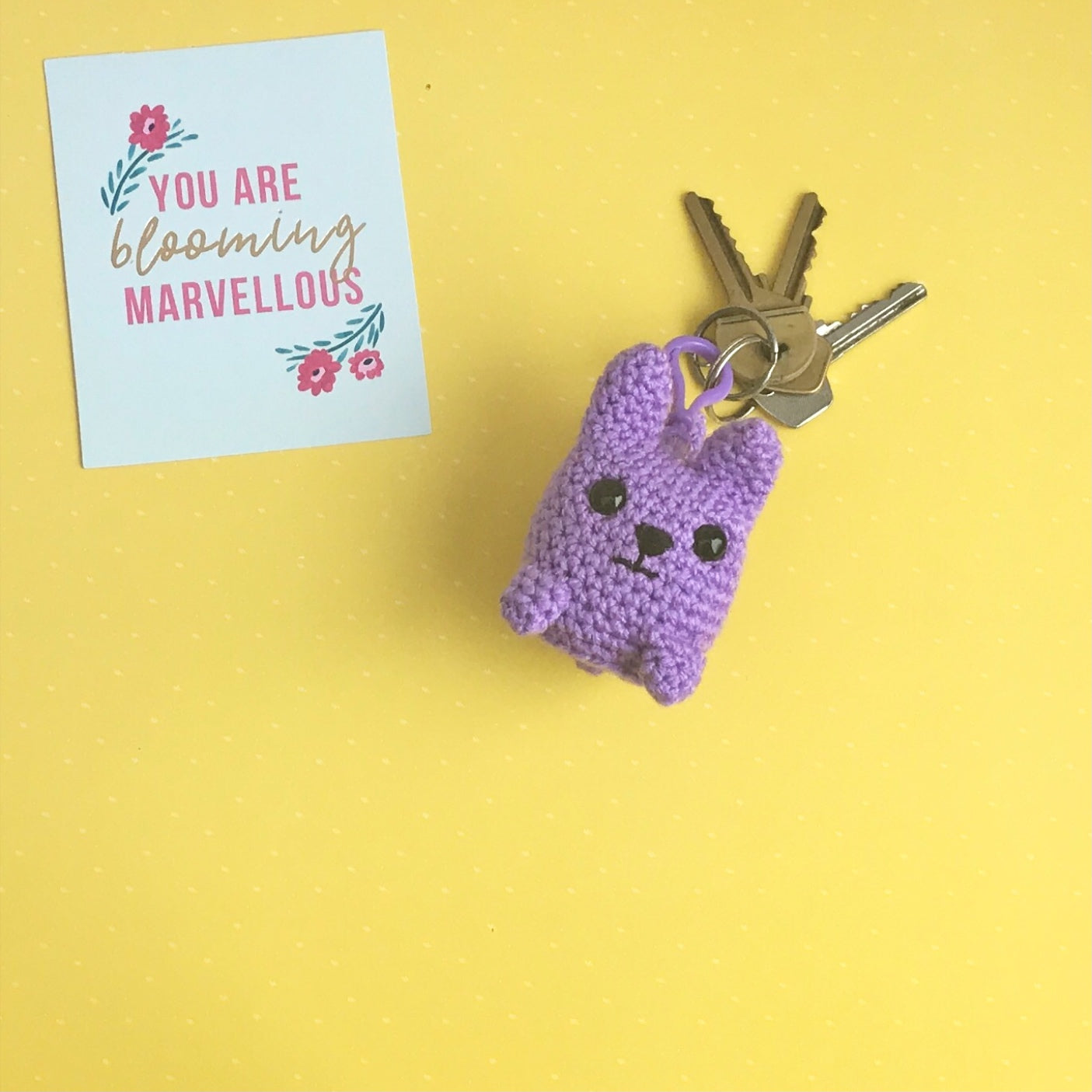 An amigurumi cat crocheted with purple yarn in a kawaii style