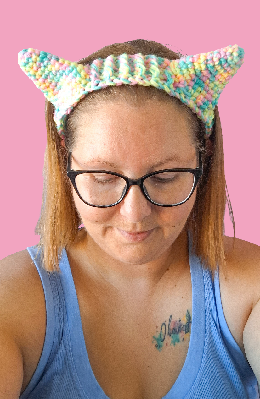 A woman wearing crochet cat ears that have been made using the pattern by crocreate. The cat ears are made with front post and back post double crochet